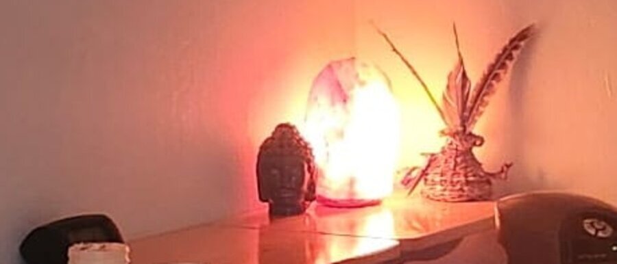 The massage room's shelf with a lit salt lamp and candles, warm ambiance