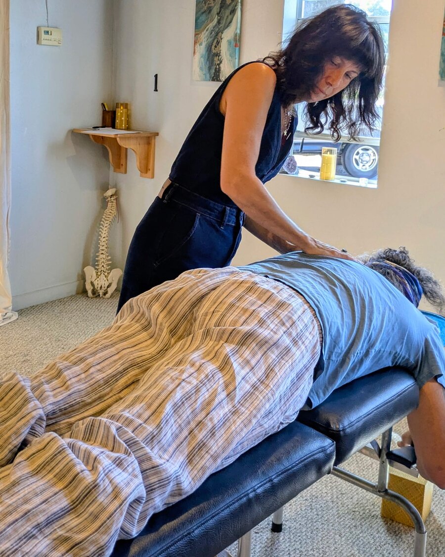 Dr. Melanie giving a Network Spinal session, hands on a client's upper back