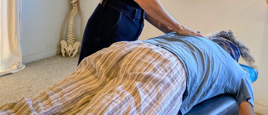 A close view of a Network Spinal session, hand resting on a client's back
